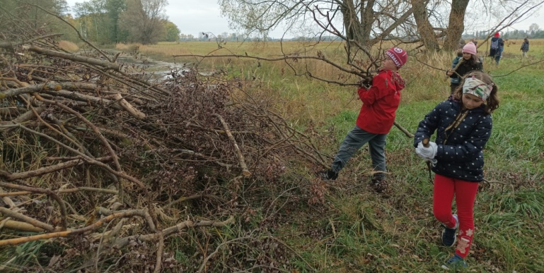 Děti hází větve na hromadu.