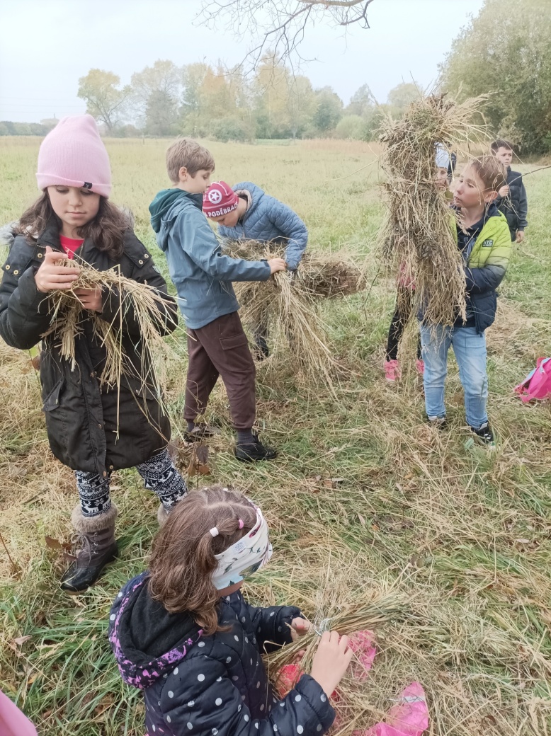 Děti vyrábějí výrobky ze suché trávy.